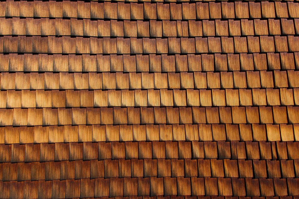 Close view of warm western red cedar shingles catching low evening light.