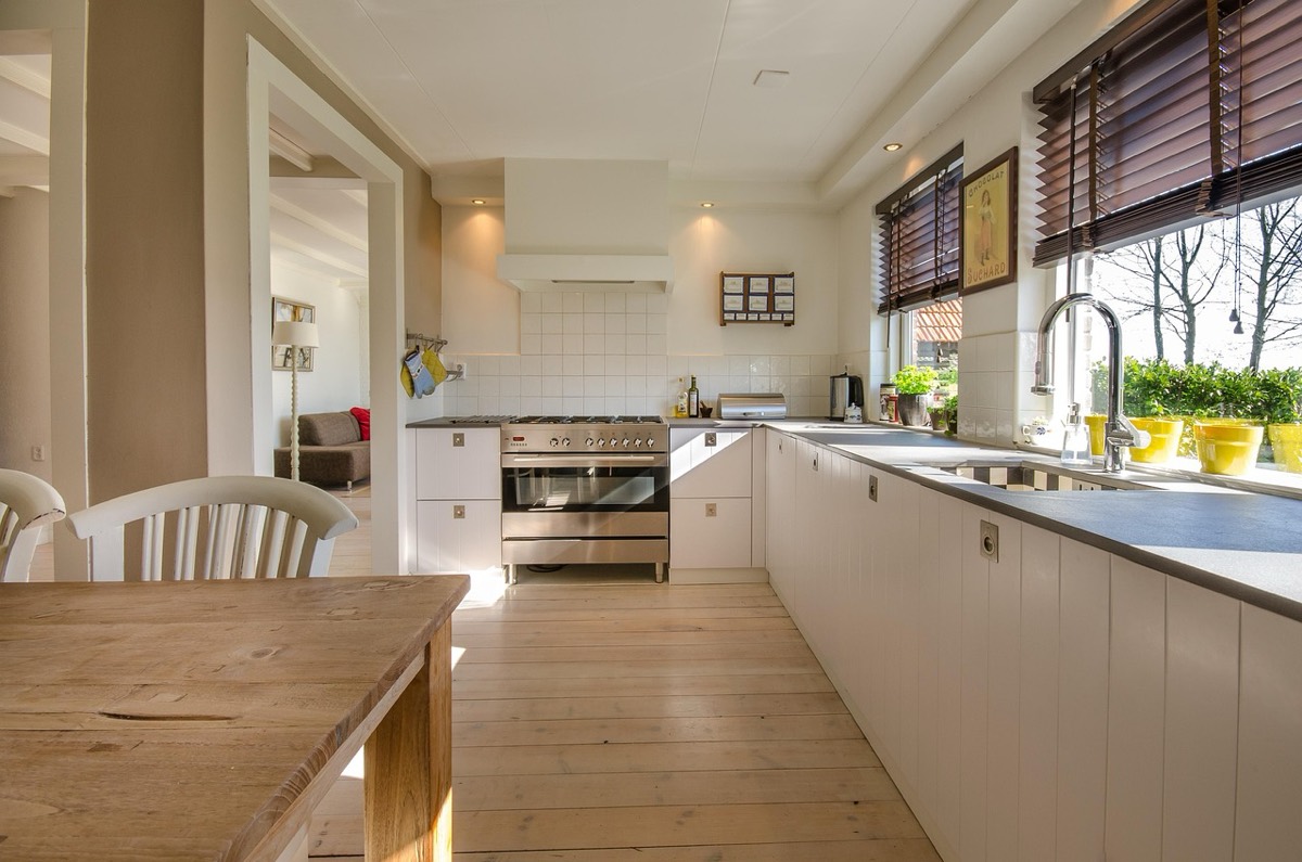 A bright kitchen with pale wood floors and daylight through a garden window.